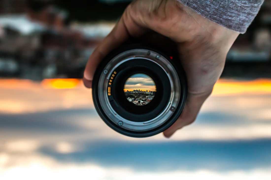 Cut out the noise and focus on the present moment with dharana. Image of lens focussing in on a city far away.